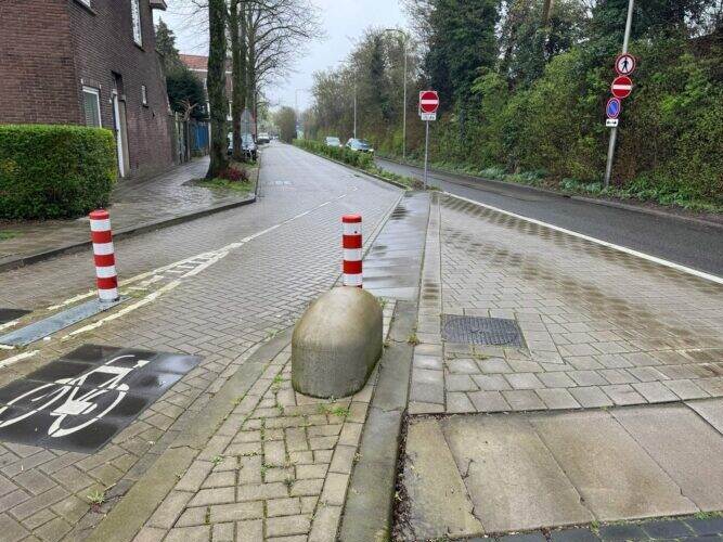 grijs fietspad met paaltjes parallel en gescheiden van een grijze autoweg